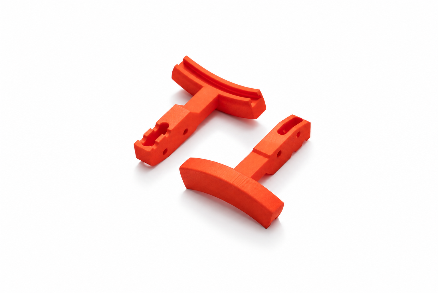 Two 3D-printed supports made of orange plastic with a curved contact surface for a mounting fixture